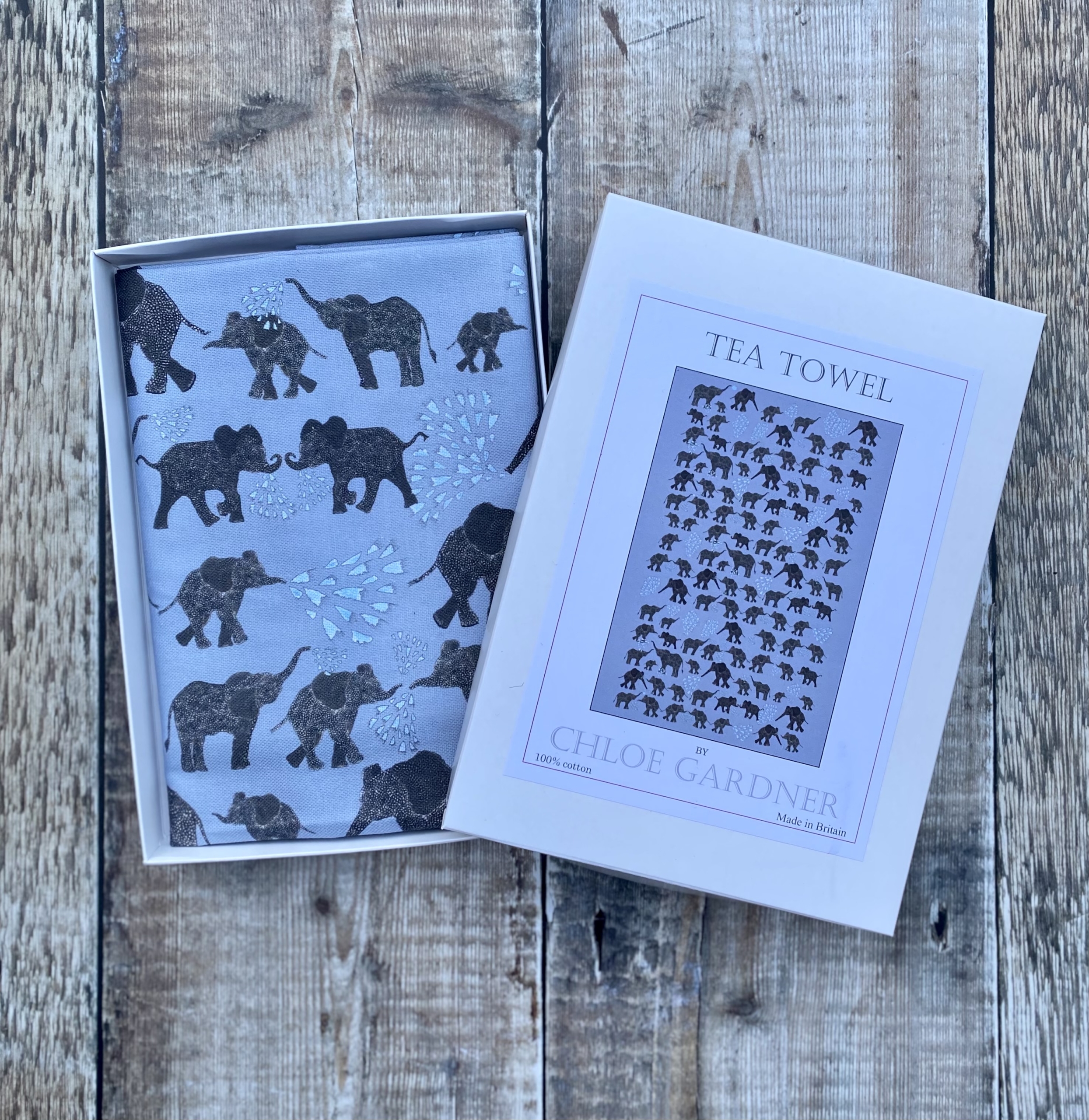 A GIFT BOXED TEA TOWEL -  LOTS OF ELEPHANTS ON GREY