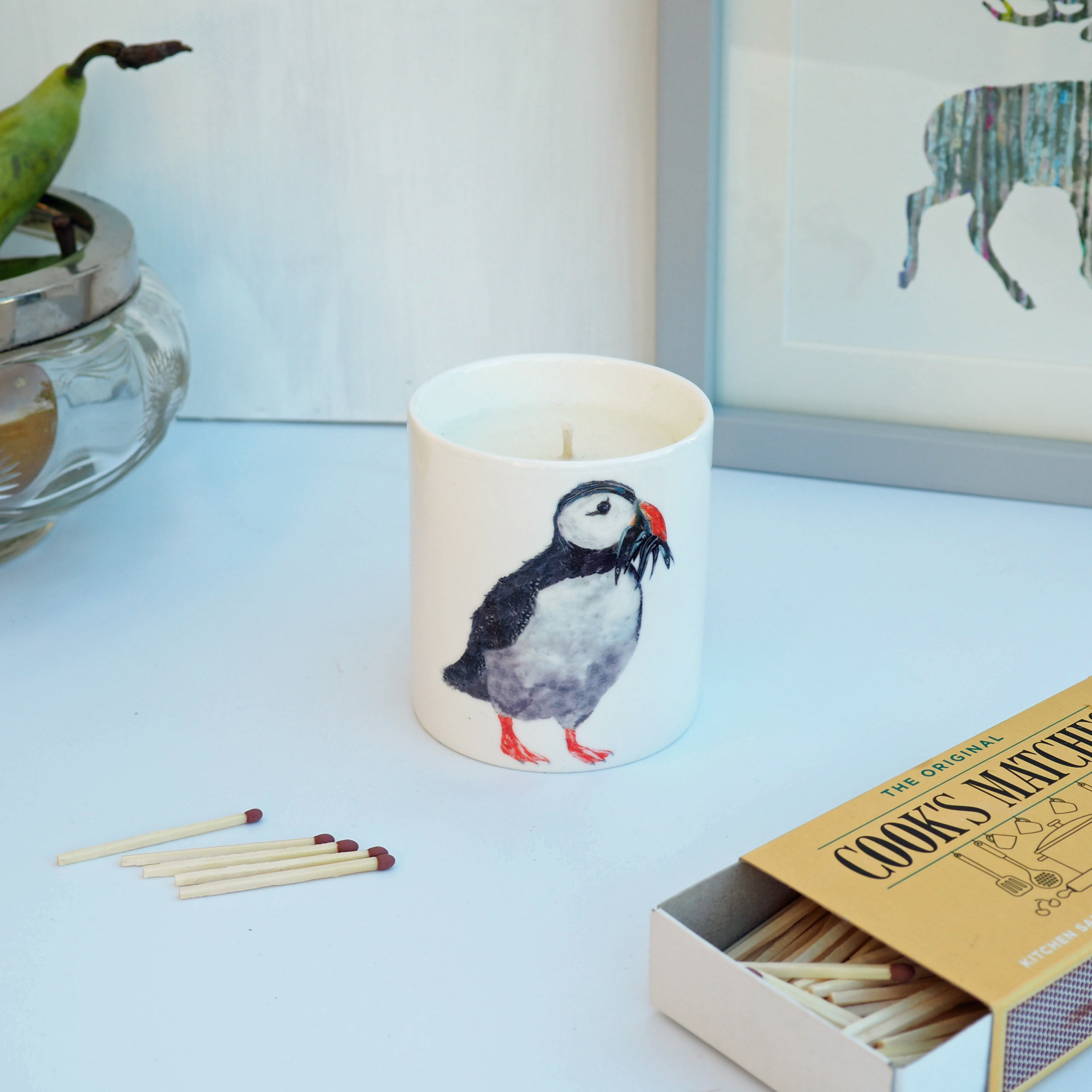 OLYMPUS DIGITAL CAMERA PUFFIN HAND POURED CERAMIC CANDLE on a table with matches