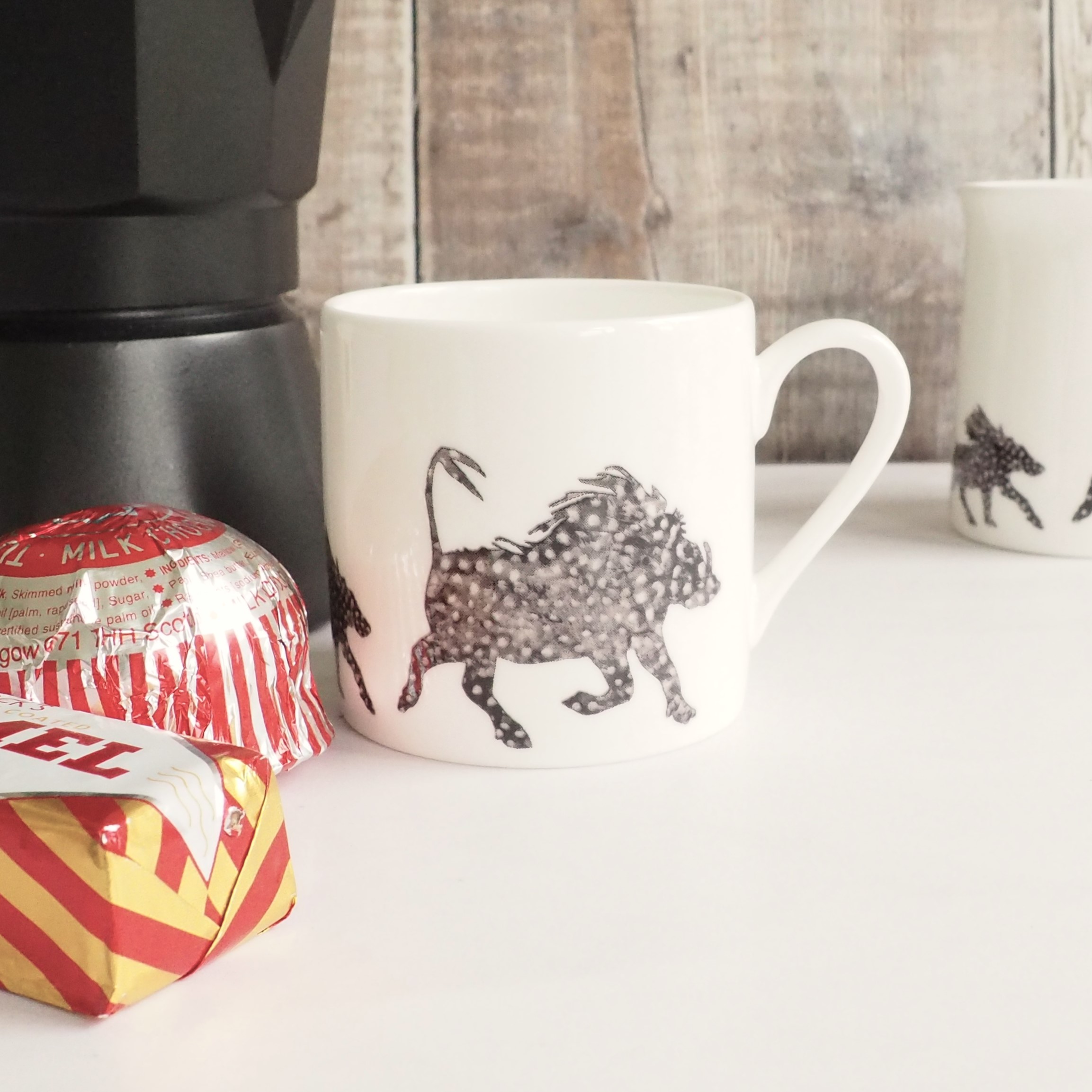 Black and white Warthog Espresso Mug by Chloe Gardner pictured with stovetop pot and Tunnocks teacakes